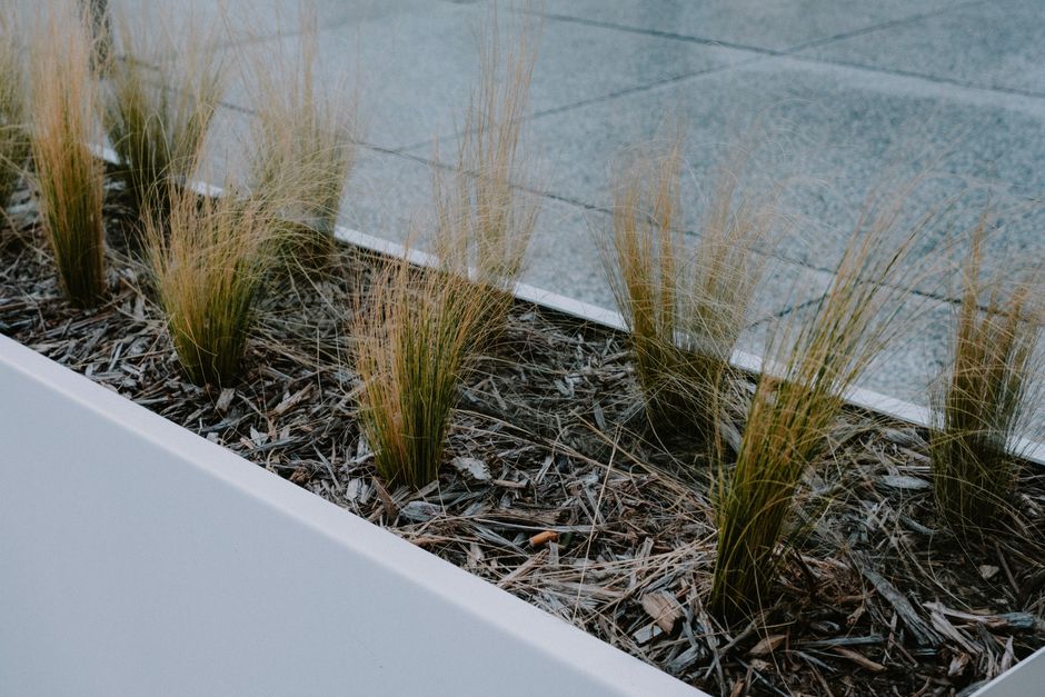 Moderne stalen plantenbakken in een sfeervolle tuin met kleurrijke bloemen en groene planten.